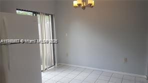 unfurnished room with light tile patterned floors, baseboards, and a chandelier