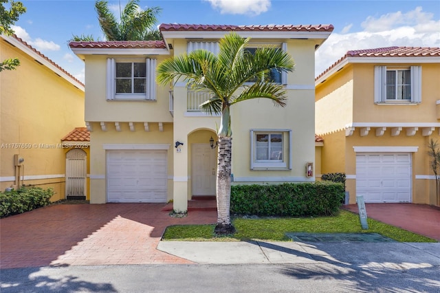 mediterranean / spanish house with stucco siding, decorative driveway, an attached garage, and a tile roof