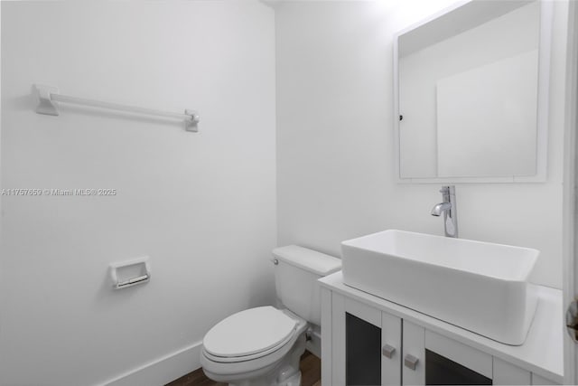 bathroom with wood finished floors, vanity, toilet, and baseboards