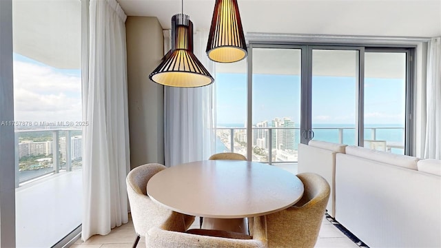 dining room with light tile patterned floors, a water view, a view of city, and a healthy amount of sunlight