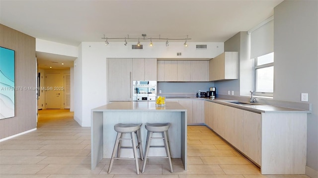 kitchen with light countertops, a breakfast bar area, a sink, and a center island