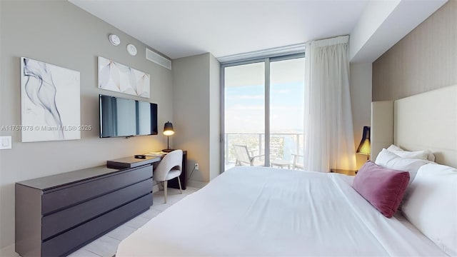 bedroom featuring light tile patterned floors, expansive windows, and built in desk