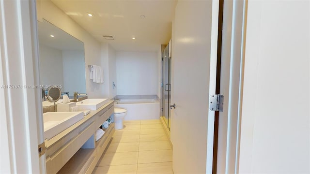 bathroom featuring double vanity, toilet, a sink, tile patterned flooring, and a bath