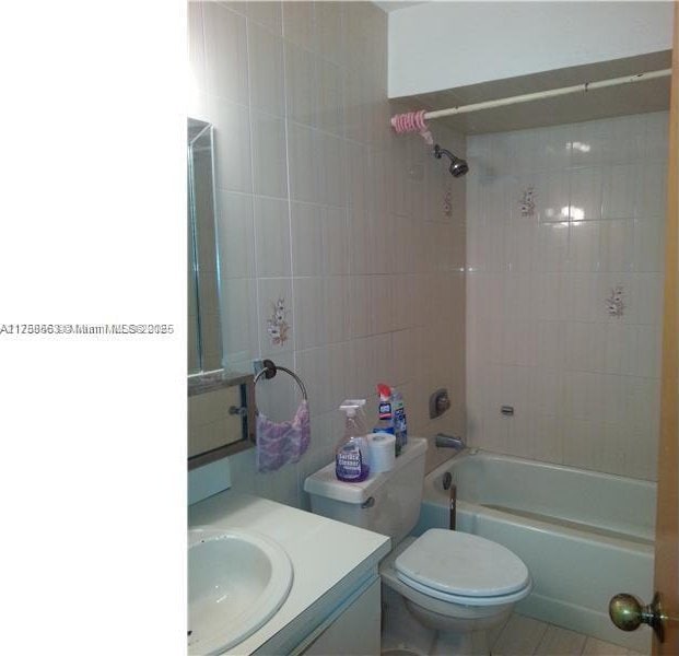 full bathroom featuring toilet, tile walls,  shower combination, tile patterned flooring, and vanity