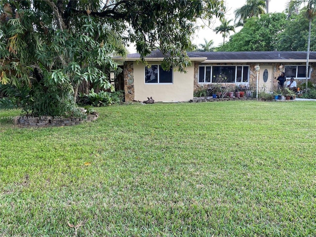 view of front of house with stone siding, a front lawn, and stucco siding