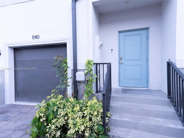 doorway to property with a garage and stucco siding