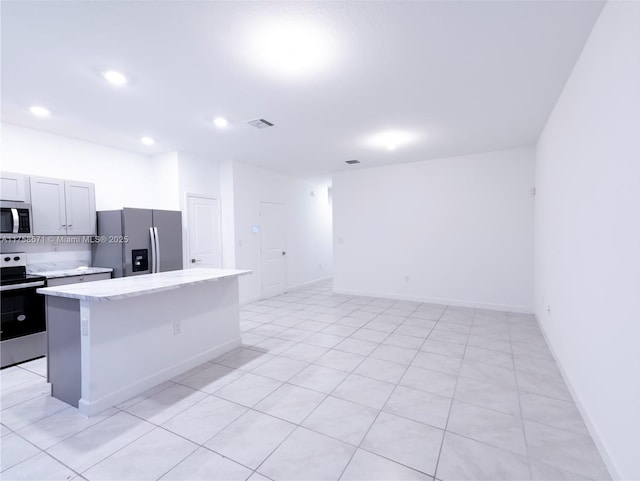 kitchen with light stone counters, recessed lighting, a kitchen island, visible vents, and appliances with stainless steel finishes