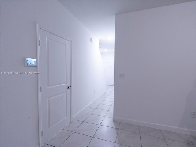 corridor featuring light tile patterned floors and baseboards