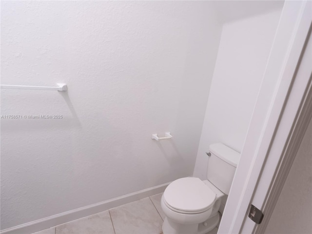 bathroom with toilet, baseboards, and tile patterned floors