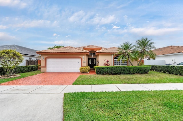 mediterranean / spanish-style house with fence, a tiled roof, decorative driveway, stucco siding, and a front yard