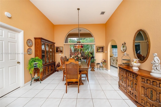 dining room featuring arched walkways, visible vents, baseboards, and light tile patterned flooring