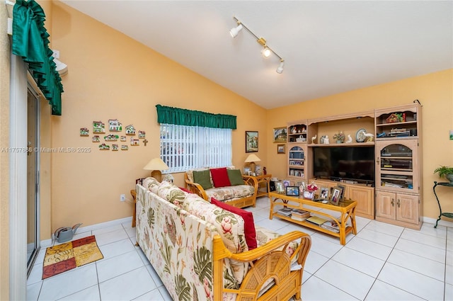 living area featuring light tile patterned floors, vaulted ceiling, baseboards, and track lighting