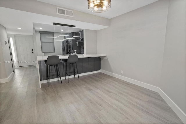 kitchen featuring visible vents, light wood-style flooring, modern cabinets, freestanding refrigerator, and light countertops