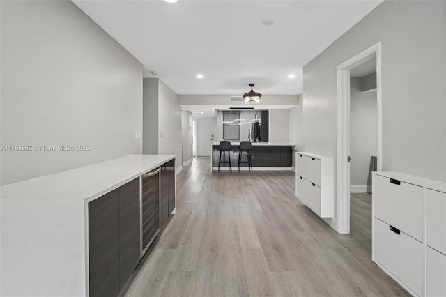 hallway with wine cooler, recessed lighting, visible vents, baseboards, and light wood finished floors