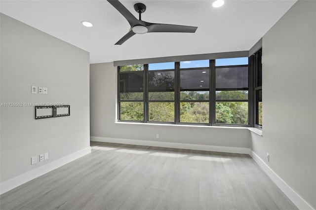 unfurnished room with recessed lighting, wood finished floors, a ceiling fan, and baseboards