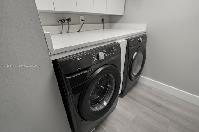 laundry area with light wood-style floors, washing machine and dryer, cabinet space, and baseboards