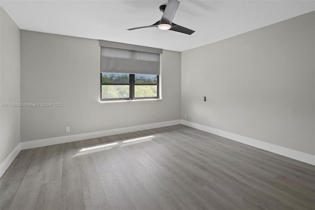 spare room with baseboards and wood finished floors