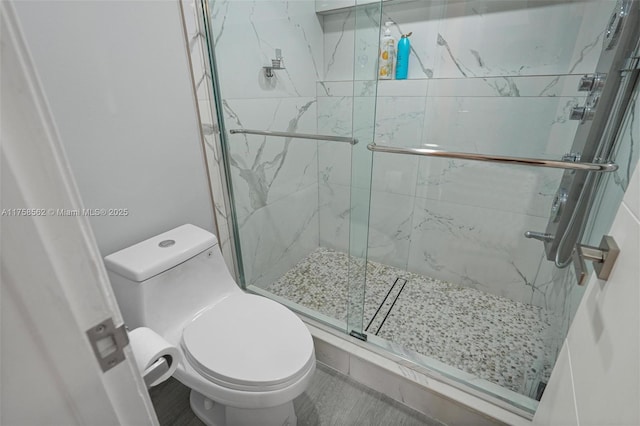 bathroom with a marble finish shower and toilet