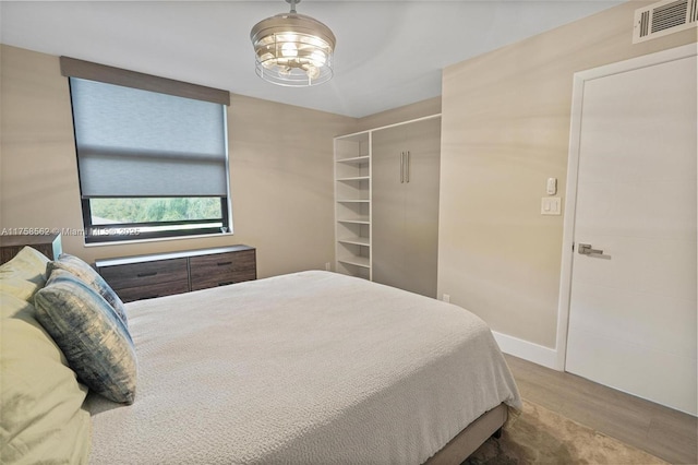 bedroom featuring visible vents, baseboards, and wood finished floors