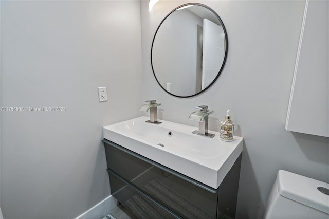 bathroom with toilet, vanity, and baseboards