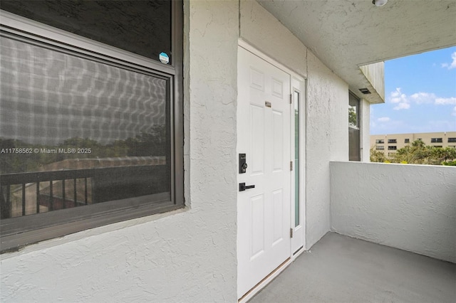 property entrance with a balcony and stucco siding