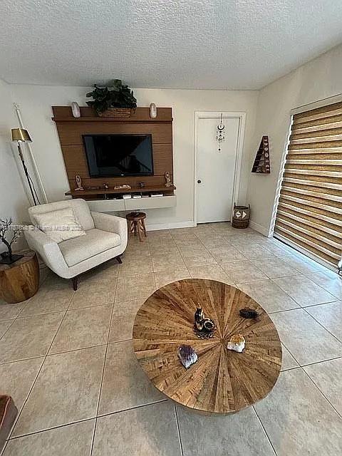 unfurnished living room with tile patterned floors, a textured ceiling, and baseboards