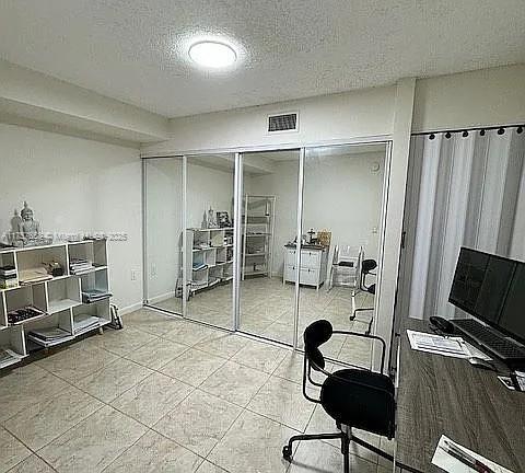 home office featuring light tile patterned floors, visible vents, baseboards, and a textured ceiling