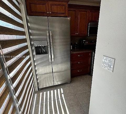 kitchen featuring light tile patterned floors, range, and stainless steel fridge with ice dispenser