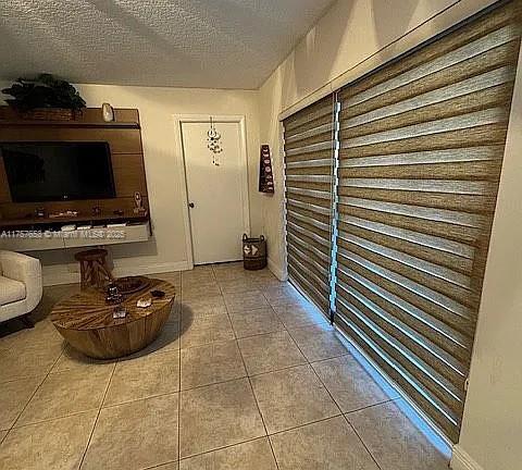 interior space featuring baseboards, a textured ceiling, and tile patterned flooring