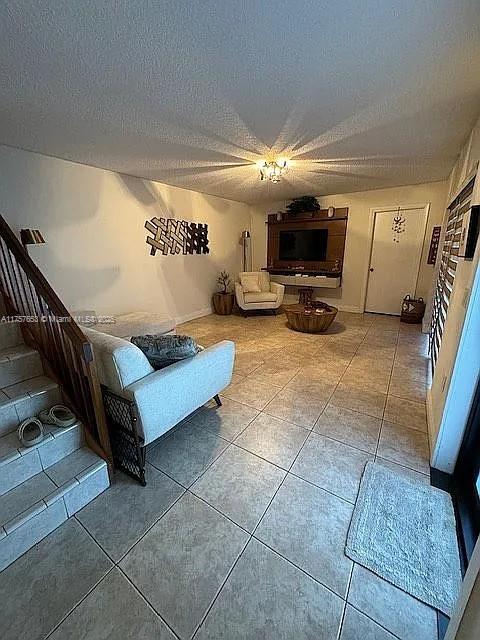 tiled living area featuring stairs and a textured ceiling