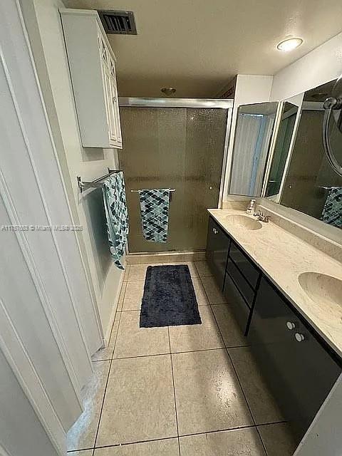 full bathroom featuring tile patterned flooring, visible vents, double vanity, and a sink