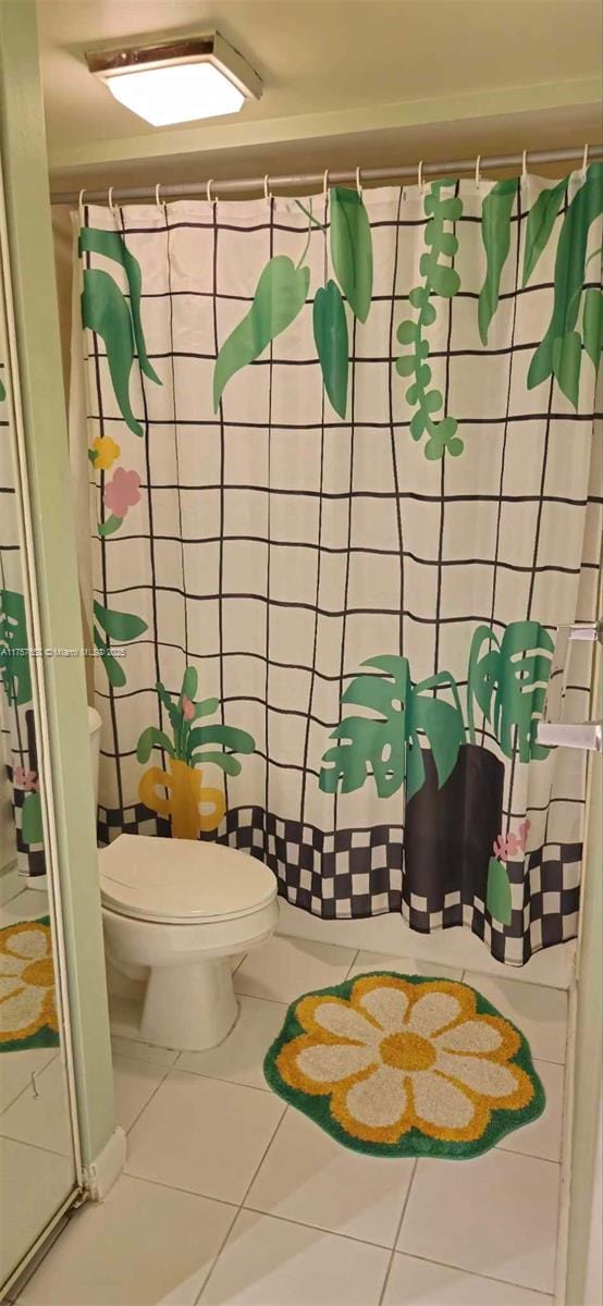 bathroom featuring tile patterned flooring, curtained shower, and toilet