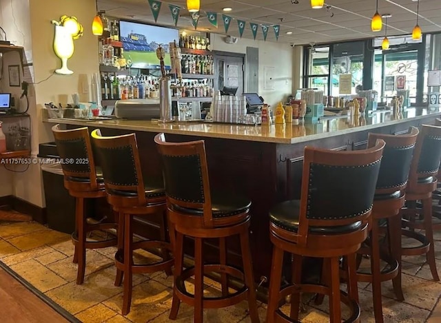 bar featuring decorative light fixtures, a community bar, and a paneled ceiling