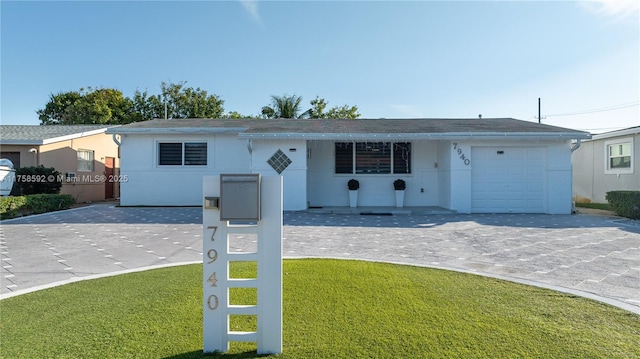 single story home with a garage, a front lawn, decorative driveway, and stucco siding