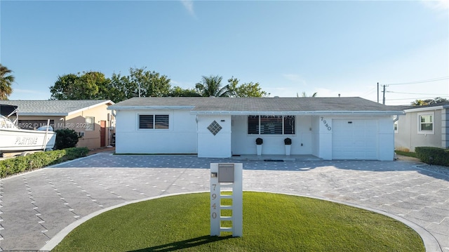 ranch-style house with a garage, a front lawn, decorative driveway, and stucco siding