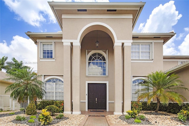 property entrance with fence and stucco siding