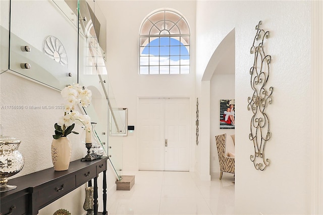 tiled foyer entrance featuring arched walkways and a high ceiling