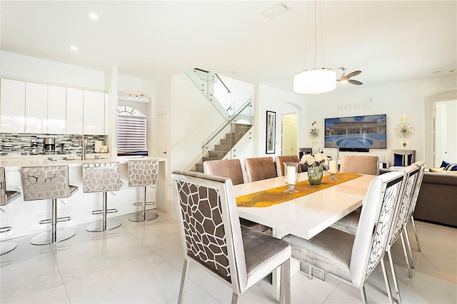 dining space featuring arched walkways, marble finish floor, recessed lighting, and stairs