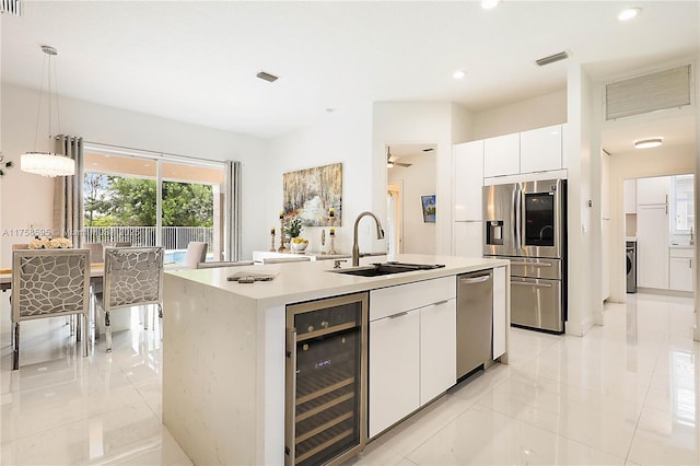 kitchen with beverage cooler, visible vents, modern cabinets, stainless steel appliances, and a sink