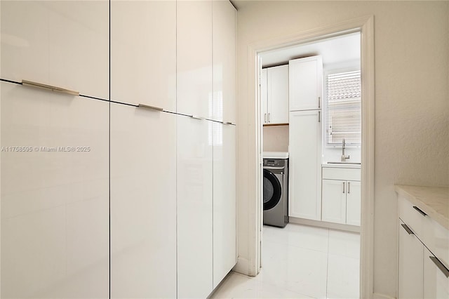 washroom with washer / dryer, cabinet space, and a sink