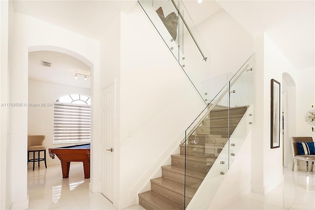 stairs featuring arched walkways, visible vents, baseboards, and tile patterned floors