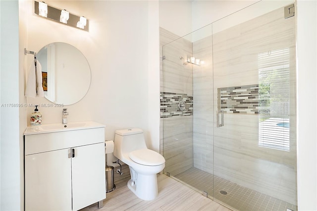 bathroom with a stall shower, vanity, and toilet