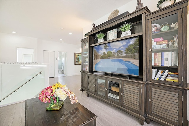 living area with baseboards, wood finished floors, and recessed lighting