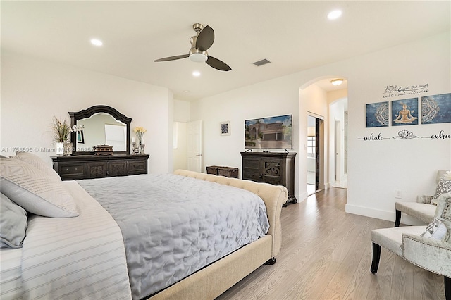 bedroom with arched walkways, light wood finished floors, and recessed lighting