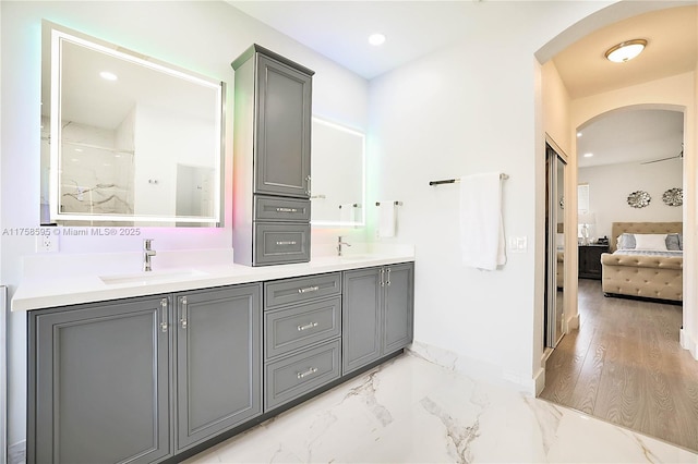 bathroom featuring marble finish floor, a sink, ensuite bath, and double vanity