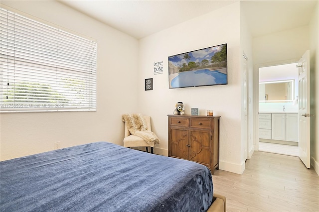 bedroom featuring light wood finished floors and baseboards