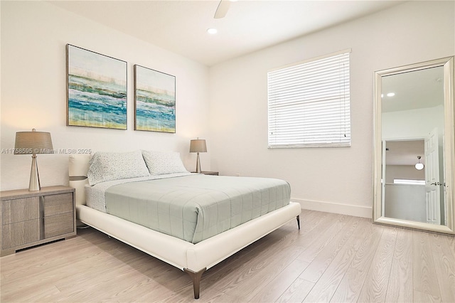 bedroom with a ceiling fan, light wood-style flooring, and baseboards