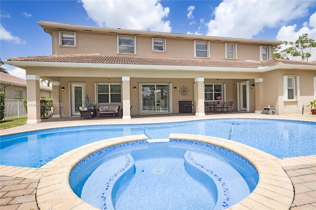 view of pool featuring a pool with connected hot tub, fence, and a patio