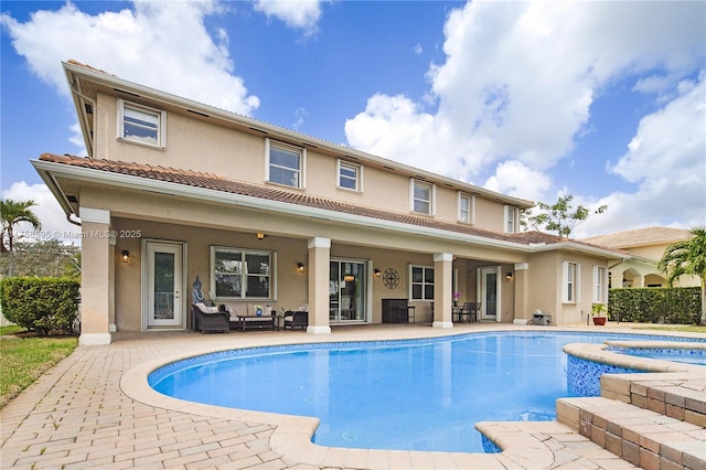 rear view of house featuring a patio, an in ground hot tub, outdoor lounge area, a fenced in pool, and stucco siding