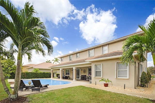 back of house with fence, a lawn, a fenced in pool, stucco siding, and a patio area